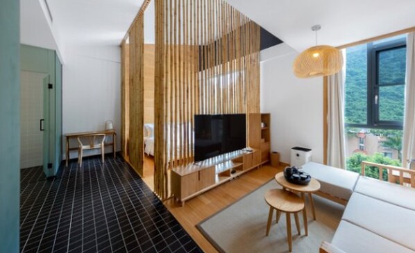 Una sala de estar moderna con televisor, muebles de madera y un ventanal grande.
