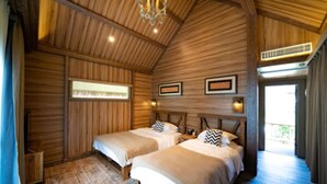 Une cabane en bois avec deux lits, un lustre, des tableaux encadrés et une fenêtre.