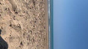 Una playa con costa rocosa y olas acercándose.