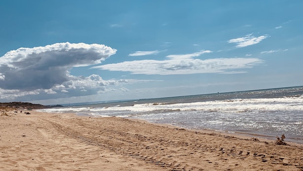Una playa con cielo despejado y olas.