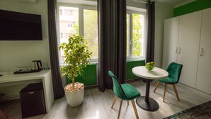 A modern room with a dining table, two chairs, a potted plant, a TV, and a cabinet.