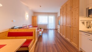 Una cocina moderna con armarios de madera, una mesa de comedor con bancos rojos y vistas a un gran ventanal con cortinas traslúcidas.