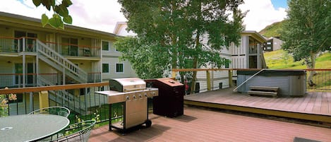 Une terrasse avec un barbecue, une table et des chaises, et une vue sur un immeuble doté de nombreux balcons.