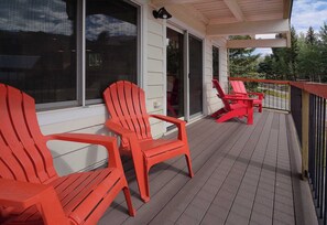 A covered deck with red chairs and a view of the surrounding area. - Elder at Outrun, Lovely remodel, hot tub, shuttle (Crested Butte)