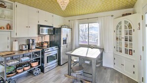 A kitchen with white cabinets, stainless steel appliances, a chandelier, and a window with a view. - Yellowstone Country Family Home w/ View & Hot Tub (Livingston)