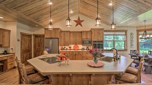 A spacious kitchen with wooden cabinets, a large island with seating, and a star decoration on the ceiling. - Bigfork Modern Living - Pet & Family Friendly! (Bigfork)