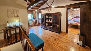A spacious room with wooden floors, a large wooden cabinet, a bench, and a staircase. - A Casa dos Avós - House with swimming pool, barbecue in the middle of nature in A Coruña. (Oza de los Ríos)