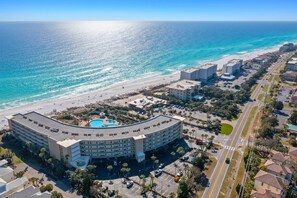 Un gran hotel con fachada curva, piscina y vistas a la playa.