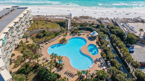 Un complexe hôtelier doté d’une grande piscine, d’un accès à la plage et d’un bâtiment avec des balcons.
