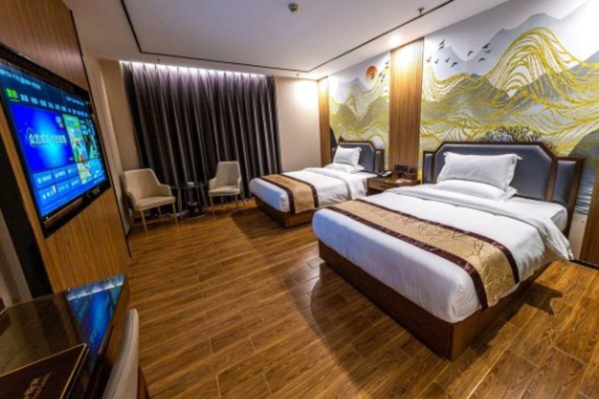 Quarto de hotel com duas camas, televisão e um mural na parede.