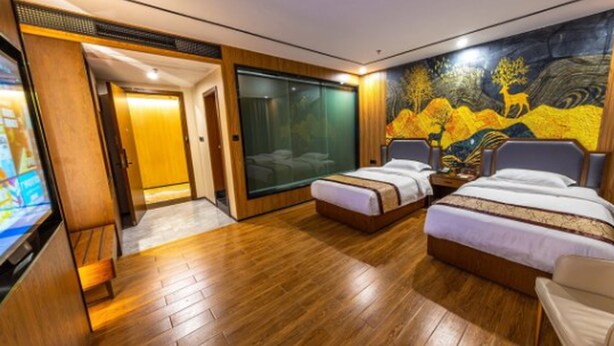 Une chambre d’hôtel moderne avec un plancher en bois, deux lits simples, une grande fenêtre et une fresque murale.