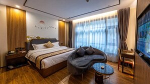 Une chambre d’hôtel moderne avec un grand lit, un canapé, une petite table et un téléviseur.