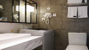 Une salle de bain avec un lavabo blanc, un miroir, un téléphone et des toilettes.