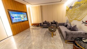 Un salon moderne avec un téléviseur à écran plat fixé sur un panneau en bois, deux canapés avec des coussins, une table basse et un élément décoratif mural.