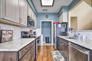 Una cucina moderna con elettrodomestici in acciaio inossidabile, un forno a microonde e una lavastoviglie. Sul bancone è presente un cartello con la scritta 'Welcome to our home'.