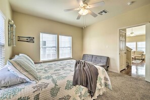 Relax in this serene bedroom with a large bed, ceiling fan, and two windows with blinds.