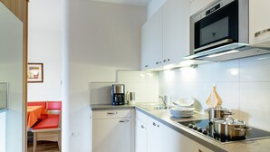 A modern kitchen with white cabinets, a built-in microwave, and a coffee maker.