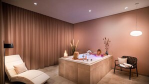 A modern spa room with a large bathtub, a lounge chair, and a small table with candles. - Superior Plus - Saline 1822, Hotel Bad Rappenau (Bad Rappenau)