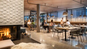A modern dining area with a fireplace, hexagonal wall design, and contemporary furniture. - Superior Plus - Saline 1822, Hotel Bad Rappenau (Bad Rappenau)