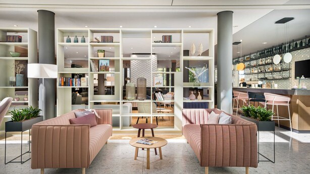 A modern interior with a central seating area, bookshelves, and a bar area. - Superior Plus - Saline 1822, Hotel Bad Rappenau (Bad Rappenau)