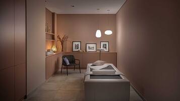 Ein moderner Wellnessraum mit Massagetisch, einem Sessel und gerahmten Bildern an der Wand.
