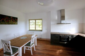 A kitchen with a wooden table and chairs, a window, and a stove.