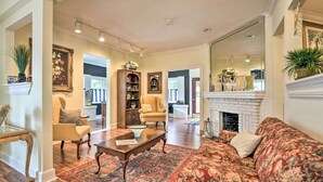 A living room with a sofa, armchair, coffee table, and fireplace. There is a bookshelf and a mirror on the wall. - Historic Green Cove Springs Home - Walk to Coast! (Green Cove Springs)