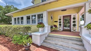 A yellow house with a front porch, steps leading up to the entrance, and potted plants. - Historic Green Cove Springs Home - Walk to Coast! (Green Cove Springs)