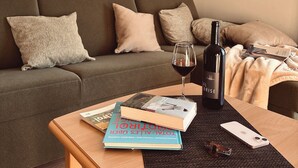 Un salón moderno con un sofá marrón, una mesa de centro de madera, una botella de vino y una copa de vino tinto.