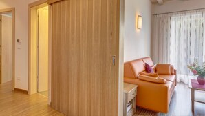 A modern room with a sliding wooden door, a sofa, and a small table with a vase.