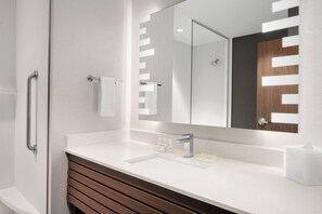 Features a sink, large mirror, and wooden vanity with a drawer.