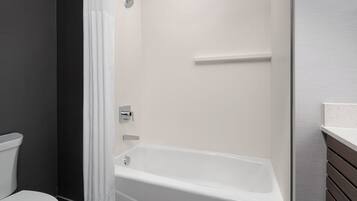 A modern bathroom with a bathtub, toilet, and shower area.