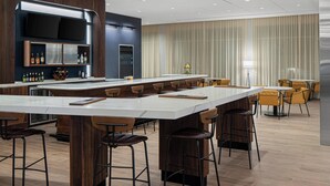 A modern bar area with a long counter, multiple stools, and a television mounted above. - Courtyard by Marriott Houston I-10 West/Memorial (Houston)
