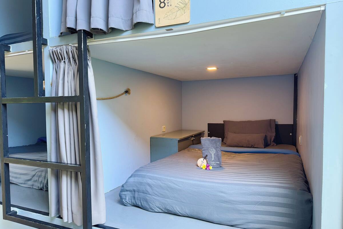 Una habitación pequeña con literas, un escritorio y una mesita de noche.