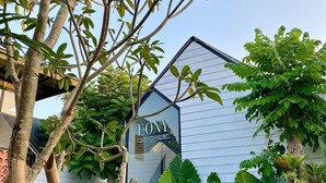 A building with a sign reading "EONY" and a garden with various plants and trees. - The Jungle Hostel Canggu (Pererenan)