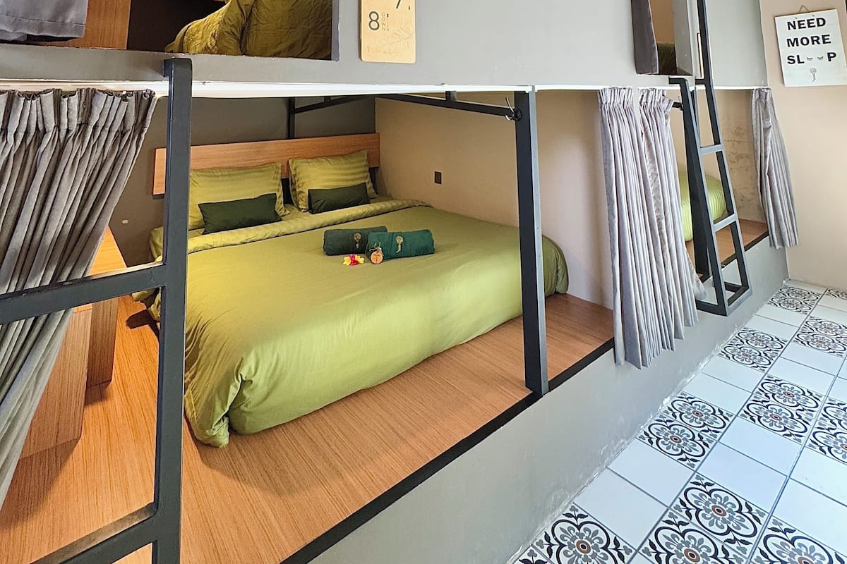 Habitación con literas, cabecera de madera, ropa de cama verde y un cartel que indica el número de habitación 78.