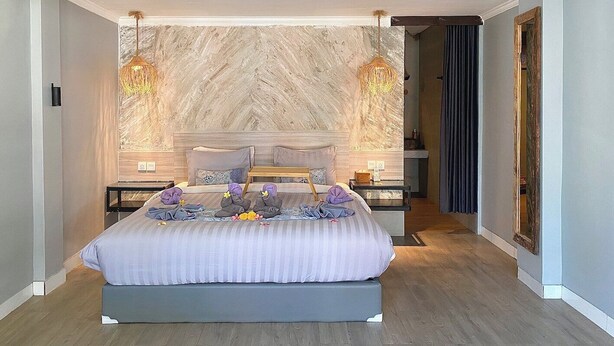 A modern bedroom with a large bed, two bedside tables, and a marble-patterned wall. - The Jungle Hostel Canggu (Pererenan)