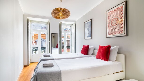 Una habitación de hotel moderna con dos camas, un ventanal grande y vistas a la ciudad.