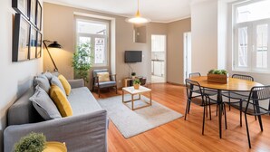 Una sala de estar moderna con un sofá gris, una mesa de centro de madera y una mesa de comedor con sillas.