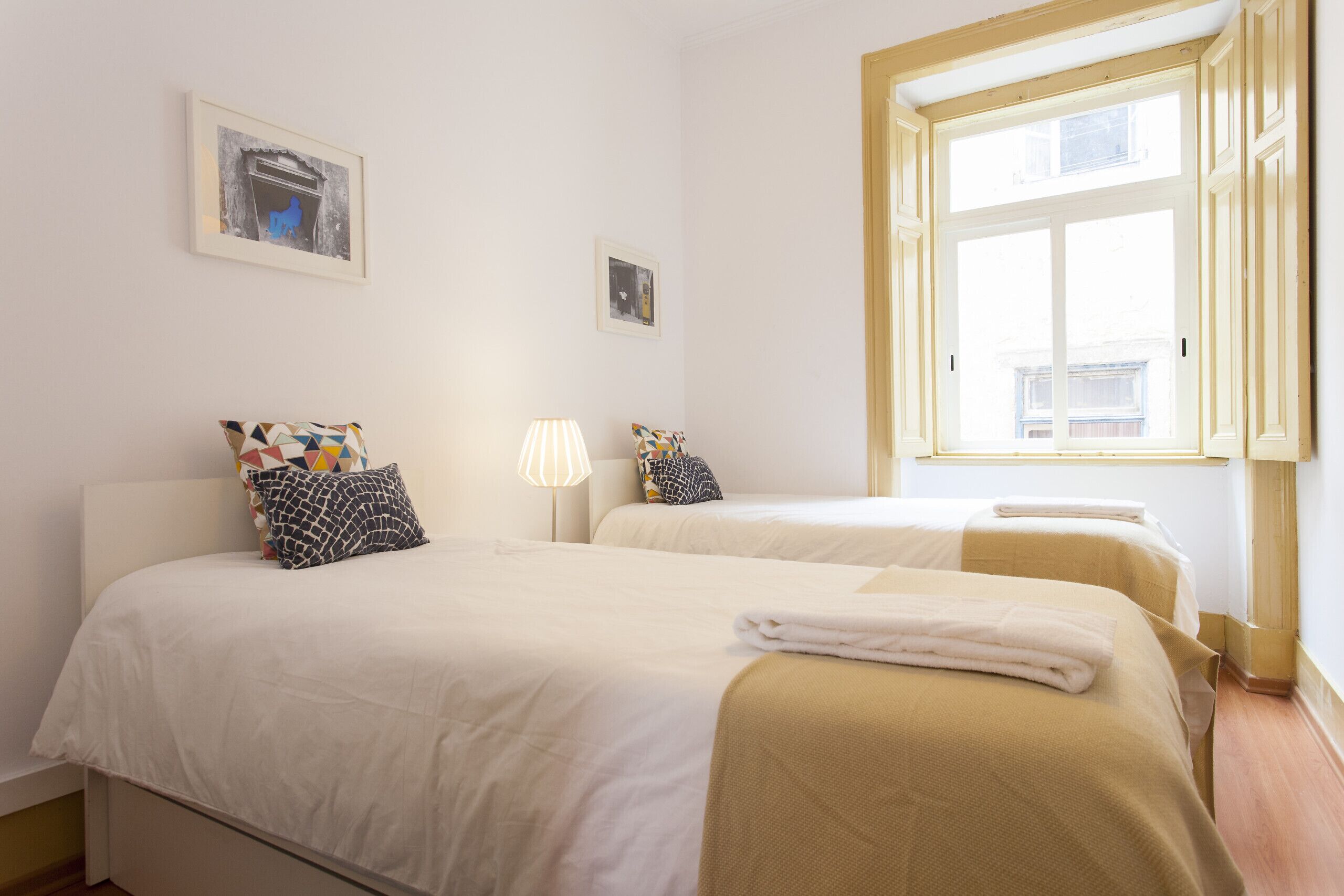 Ein Hotelzimmer mit zwei Betten, einem Fenster und einer Lampe.