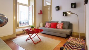 A living room with a sofa, a red table, a floor lamp, and a patterned rug. - Central Downtown Rossio by Central Hill (Lisboa ciudad)