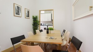 A dining area with a wooden table, chairs, a bottle of wine, keys, and a magazine. - Central Downtown Rossio by Central Hill (Lisboa ciudad)