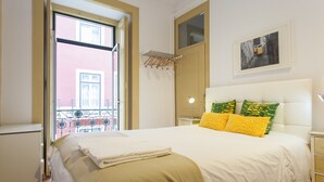 A bedroom with a bed, a nightstand, a lamp, a window with a view, and a wall-mounted drying rack. - Central Downtown Rossio by Central Hill (Lisboa ciudad)
