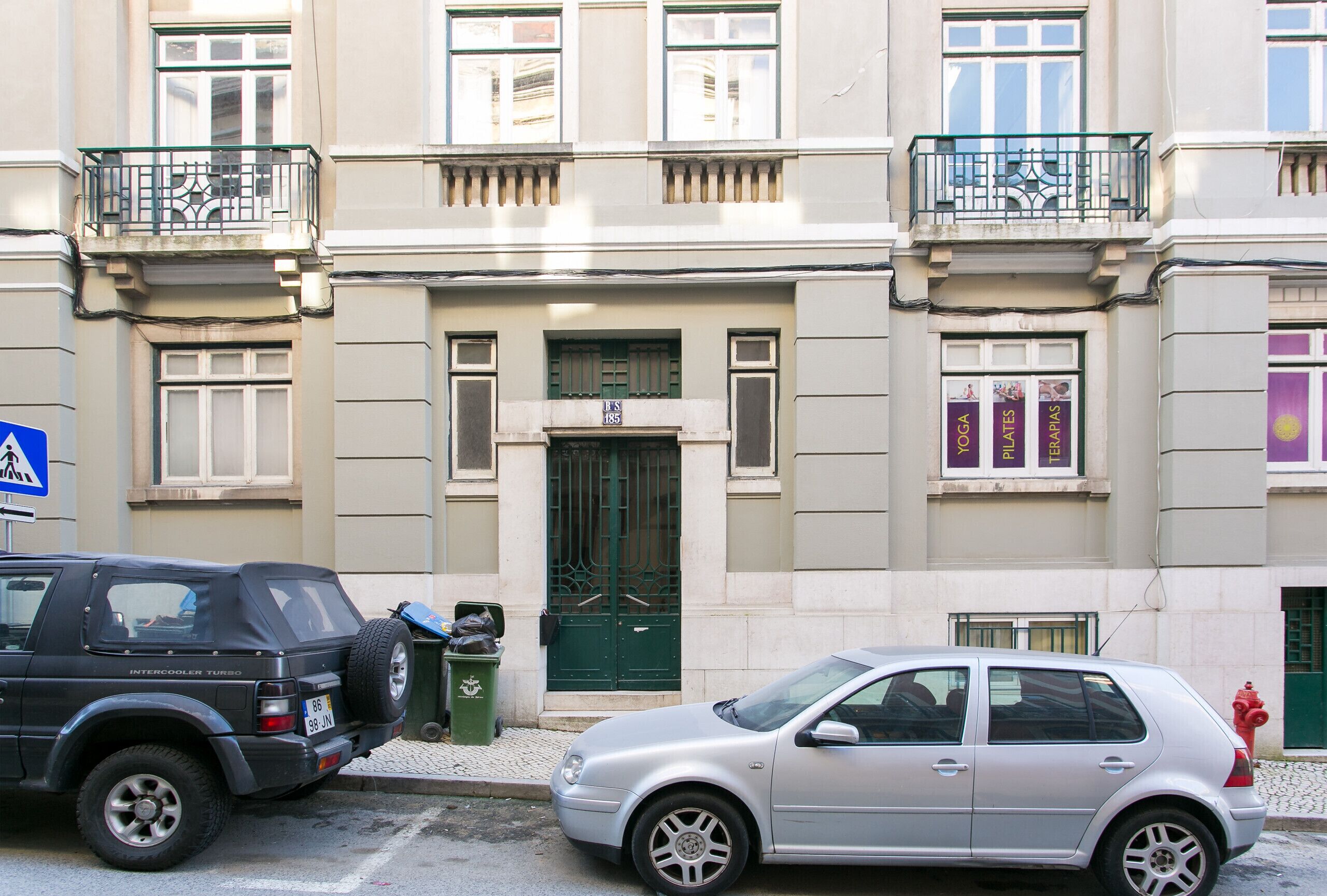 Ein Gebäude mit einer grünen Tür, einem Schild darüber und einem Balkon mit Geländer.