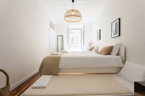 Un dormitorio minimalista con una cama grande, una mesita de noche, una silla y una lámpara colgante.