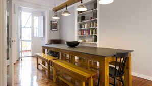 Una cocina con una mesa de madera, bancos y una estantería.