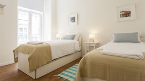 Un dormitorio con dos camas, una ventana y una alfombra pequeña.