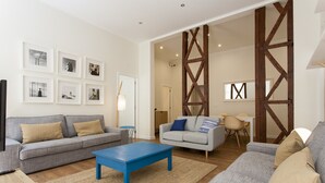 Una sala de estar con dos sofás grises, una mesa de centro azul y cuadros enmarcados en la pared.