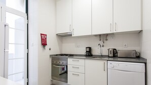 A modern kitchen with white cabinets, a built-in oven, a dishwasher, and a coffee maker.