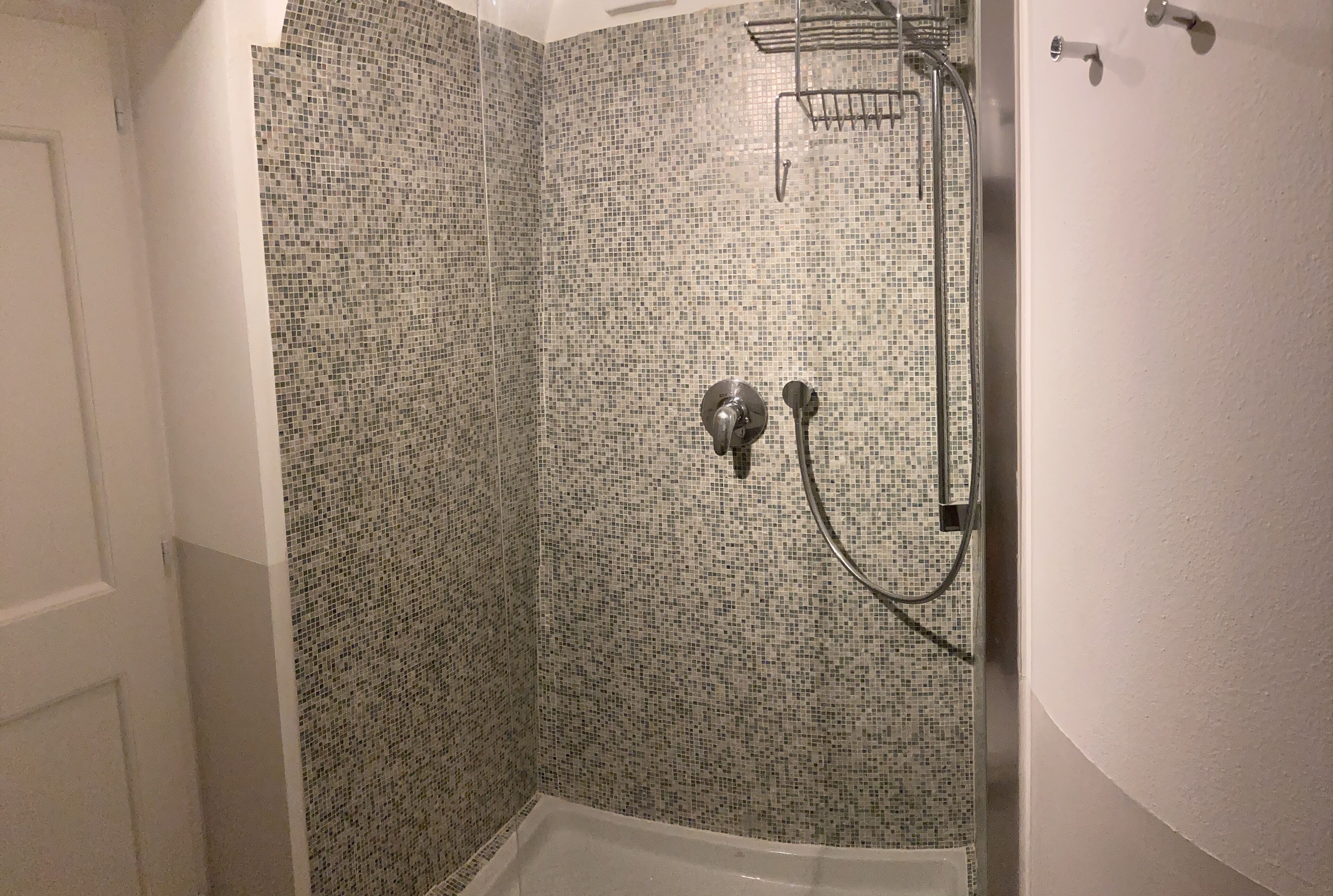 A shower area with mosaic tile walls and a bathtub.